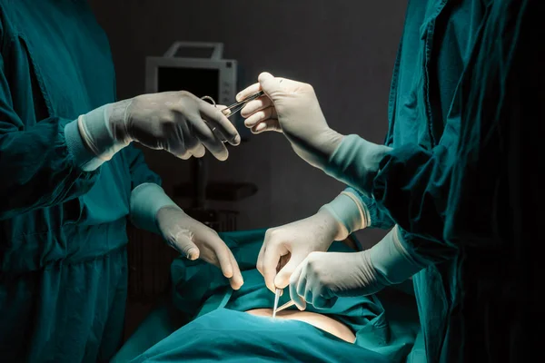 手術チームのイメージ手術を行い 看護師が手術室のコンセプトに賛同 協力しながら滅菌はさみを外科医に手渡す — ストック写真