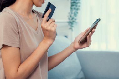 Contented young woman eagerly makes an online purchase using her smartphone. E-commerce business, online purchasing.