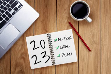 2023 Mutlu Yeni Yıl Kararları Hedef Listesi ve Planları Ayarlama - Yeni yıl hedefleri ve kararları planlama hakkında not defteriyle birlikte iş yeri masası. Değişim ve kararlılık kavramı.