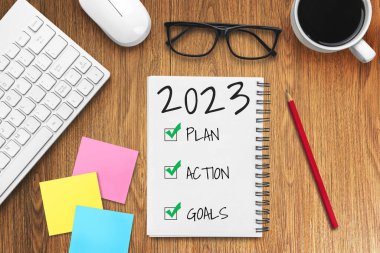 2023 Mutlu Yeni Yıl Kararları Hedef Listesi ve Planları Ayarlama - Yeni yıl hedefleri ve kararları planlama hakkında not defteriyle birlikte iş yeri masası. Değişim ve kararlılık kavramı.