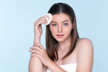 Facial cosmetic makeup concept. Portrait of young charming girl applying dry powder foundation. Beautiful girl smiling with perfect skin putting cosmetic makeup on her face.