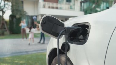 İlerici ebeveynler kızlarını okuldan alırken elektrikli araba ve yenilenebilir enerji kavramını kullandılar, evdeki EV otomobil için şarj istasyonu. Alternatif eko taşımacılığı.