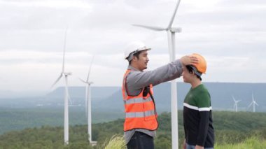 Oğluyla birlikte kırsal kesimdeki bir tepenin tepesinde ya da dağda bir rüzgar çiftliğinde mühendis. Yenilenebilir ve sürdürülebilir enerjinin gelecekteki üretimi için yenilikçi bir ideal. Rüzgar türbininden enerji üretimi.