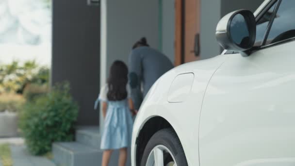 電気自動車用の家庭用充電ステーションからプラグを取り付ける進歩的な父と娘 クリーンエネルギーの再生可能エネルギーを搭載したEvカーを搭載した未来のエコカー — ストック動画