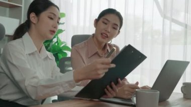 Ofis çalışma alanında birlikte çalışan iki genç hevesli iş kadını. Genç meslektaşlar tartışırken ve dizüstü bilgisayar kullanırken. Modern ofis çalışanları masada birlikte oturuyorlar..