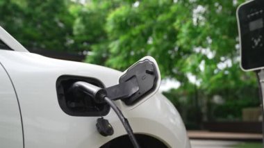 Yakın çekim yenilikçi modern ulaşım konsepti, elektrikli araba şarj istasyonunda gökyüzünden yansıyan yüksek detay ile şarj ediliyor. Yenilenebilir enerji tarafından kullanılan çevre dostu elektrikli araç.