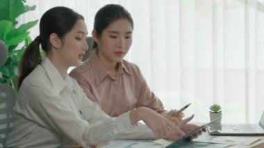 Ofis çalışma alanında birlikte çalışan iki genç hevesli iş kadını. Genç meslektaşlar tartışırken ve dizüstü bilgisayar kullanırken. Modern ofis çalışanları masada birlikte oturuyorlar..