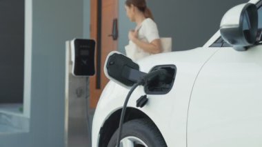 Bir kadın evinde elektrikli araç şarj aletinin fişini çekiyor. İlerici bir yaşam tarzında elektrikli araçların kullanımı, temiz ve sağlıklı bir çevreye katkıda bulunur..