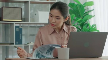 Ofiste çalışan ve dizüstü bilgisayar yazan hevesli bir iş kadını. Masasında oturmuş laptopla çalışan güzel bir ofis hanımı..