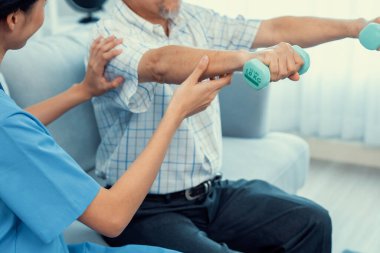 Contented senior patient doing physical therapy with the help of his caregiver. Senior physical therapy, physiotherapy treatment, nursing home for the elderly