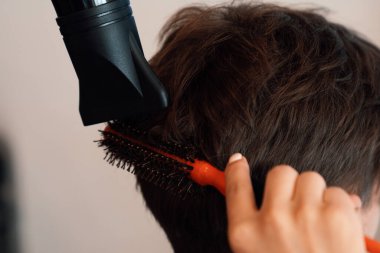 Yakın plan Asyalı kadın berber, kaliteli berber dükkanında erkek saç stili olan müşteriler için saç kesimi yapıyor. Makasla erkek saç stili ve kuaför salonu konseptinde tarak..