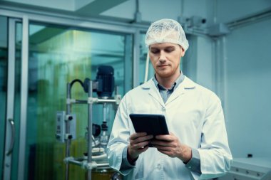 Erkek bilim adamı, esrar çıkarma laboratuarında çalışan eczacı kenevir yaprağı ve kenevir bitkilerinden alınan kimya bilgilerini içeren tablet taşıyor. Tıbbi esrar özütü.