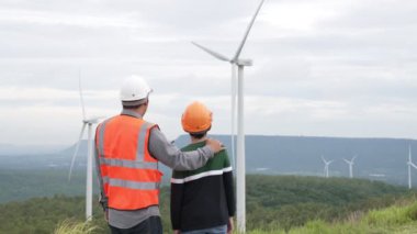 Oğluyla birlikte kırsal kesimdeki bir tepenin tepesinde ya da dağda bir rüzgar çiftliğinde mühendis. Yenilenebilir ve sürdürülebilir enerjinin gelecekteki üretimi için yenilikçi bir ideal. Rüzgar türbininden enerji üretimi.