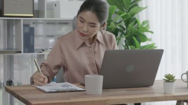 Ofiste çalışan ve dizüstü bilgisayar yazan hevesli bir iş kadını. Masasında oturmuş laptopla çalışan güzel bir ofis hanımı..