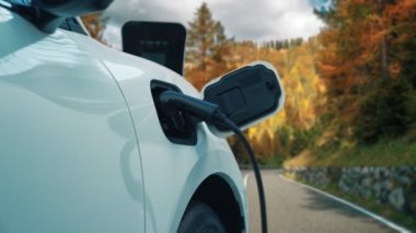 Tepe yolundaki şarj istasyonunda elektrikli arabanın çevresel farkındalığı için yenilikçi bir kavram. EV araba temiz çevre için yenilenebilir enerjiden güç alıyor.