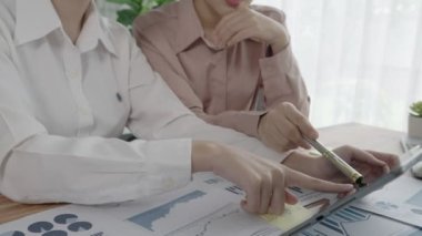 Ofis çalışma alanında birlikte çalışan iki genç hevesli iş kadını. Genç meslektaşlar tartışırken ve dizüstü bilgisayar kullanırken. Modern ofis çalışanları masada birlikte oturuyorlar..