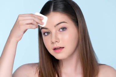 Facial cosmetic makeup concept. Portrait of young charming girl applying dry powder foundation. Beautiful girl smiling with perfect skin putting cosmetic makeup on her face.