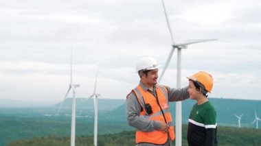 Oğluyla birlikte kırsal kesimdeki bir tepenin tepesinde ya da dağda bir rüzgar çiftliğinde mühendis. Yenilenebilir ve sürdürülebilir enerjinin gelecekteki üretimi için yenilikçi bir ideal. Rüzgar türbininden enerji üretimi.