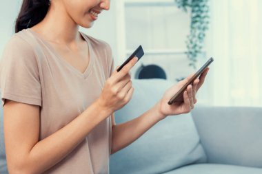 Contented young woman eagerly makes an online purchase using her smartphone. E-commerce business, online purchasing.