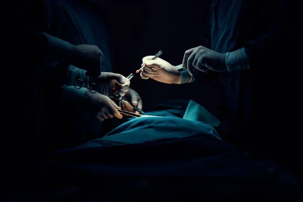 滅菌手術室で患者に手術を行う外科チームを閉鎖します ランプに照らされた手術室では 専門家と自信のある外科チームが無意識の患者に医療を提供します — ストック写真