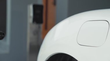 İlerici adam evindeki elektrikli aracın aküsüne emisyonsuz güç bağlantısı kuruyor. Elektrikli araç elektrik istasyonundan EV araba aküsüne kabloyla şarj oluyor.