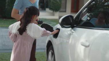 Evde şarj edilen elektrikli bir araçla okuldan yeni dönen anne ve kızın ilerici yaşam tarzı. Elektrikli araç, sürdürülebilir temiz enerjiyle çalışıyor..
