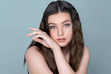 Young charming brunette sweet smiling, posing hand gesture for beauty and cosmetic concept advertising. Beautiful young girl with perfect long hair and flawless clean fresh skin.