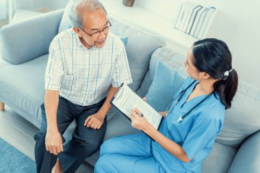 A young female doctor inquires about personal information of a contented senior at home. Medical care for the elderly, elderly illness, and nursing homes, home care.