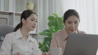 Ofis çalışma alanında birlikte çalışan iki genç hevesli iş kadını. Genç meslektaşlar tartışırken ve dizüstü bilgisayar kullanırken. Modern ofis çalışanları masada birlikte oturuyorlar..
