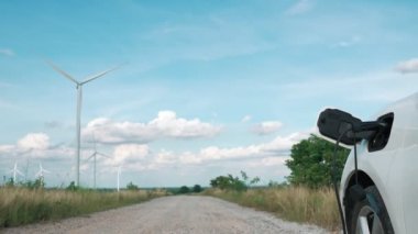 Çevreyi korumak için rüzgar türbininden yeşil ve yenilenebilir enerjiyle çalışan şarj istasyonunda şarj edilen gelişmiş gelecek enerji altyapısı konsepti.