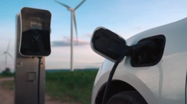 Çevreyi korumak için rüzgar türbininden yeşil ve yenilenebilir enerjiyle çalışan şarj istasyonunda şarj edilen gelişmiş gelecek enerji altyapısı konsepti.