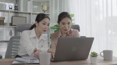 Ofis çalışma alanında birlikte çalışan iki genç hevesli iş kadını. Genç meslektaşlar tartışırken ve dizüstü bilgisayar kullanırken. Modern ofis çalışanları masada birlikte oturuyorlar..