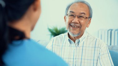A young female doctor inquires about personal information of a contented senior at home. Medical care for the elderly, elderly illness, and nursing homes, home care.