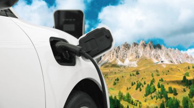 Elektro jeneratör sürücüsüyle enerji sürdürülebilir araba gücü, şarj istasyonunda şarj edilen batarya, ilerici seyahat konsepti için dağ zeminine sahip. Temiz ortamın sembolü olarak doğadaki EV otomobil.