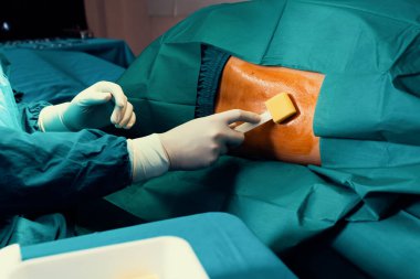 Doktor ya da cerrah ameliyat yapmadan önce ağrıyı azaltmak için hastaya anestezi için betadin uygular. Steril operasyon tiyatro konseptinde tıbbi cerrahi hazırlık prosedürü.