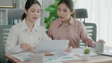 Ofis çalışma alanında birlikte çalışan iki genç hevesli iş kadını. Genç meslektaşlar tartışırken ve dizüstü bilgisayar kullanırken. Modern ofis çalışanları masada birlikte oturuyorlar..