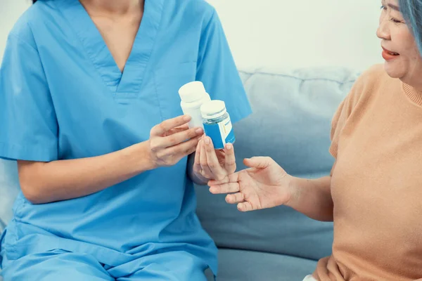 stock image Caregiver advising contented senior woman on medication in the living room. Medication for seniors, nursing house, healthcare at home.