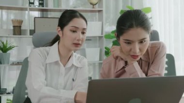 Ofis çalışma alanında birlikte çalışan iki genç hevesli iş kadını. Genç meslektaşlar tartışırken ve dizüstü bilgisayar kullanırken. Modern ofis çalışanları masada birlikte oturuyorlar..