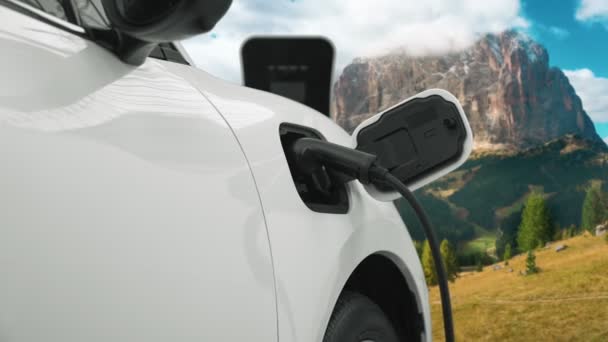 クリーンな環境のためのクリーンエネルギーによって駆動電気自動車の進歩的な概念の背景として山の上の空に雲の時間経過と自然景観 充電ステーションでのEv車の充電 — ストック動画