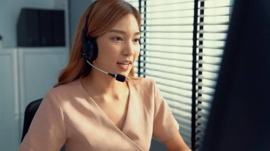 Competent female operator working on computer and while talking with clients. Concept relevant to both call centers and customer service offices.