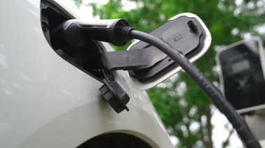 Yakın çekim yenilikçi modern ulaşım konsepti, elektrikli araba şarj istasyonunda gökyüzünden yansıyan yüksek detay ile şarj ediliyor. Yenilenebilir enerji tarafından kullanılan çevre dostu elektrikli araç.
