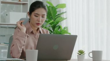 Ofiste çalışan ve dizüstü bilgisayar yazan hevesli bir iş kadını. Masasında oturmuş laptopla çalışan güzel bir ofis hanımı..