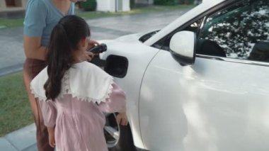 Evde şarj edilen elektrikli bir araçla okuldan yeni dönen anne ve kızın ilerici yaşam tarzı. Elektrikli araç, sürdürülebilir temiz enerjiyle çalışıyor..
