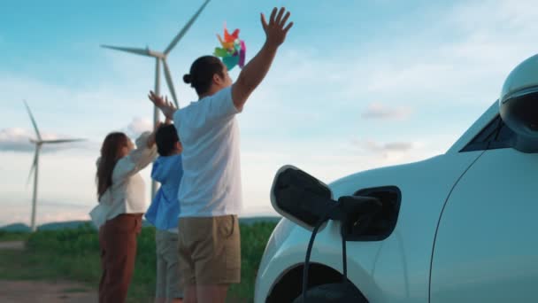 渐进式快乐家庭的概念 享受他们在风电场与电动汽车的时光 充电站风力涡轮机洁净可再生能源驱动的电动汽车 — 图库视频影像