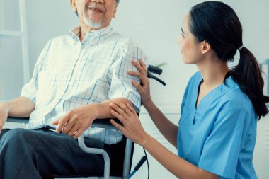 Happy positive asian nurse giving support and touching contented senior man with love. Nursing home for the elderly, elderly health and illness, senior patient carer.