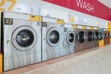 Halka açık bir mağazada kaliteli para ile çalışan bir dizi çamaşır makinesi. Kamu dairesinde ticari çamaşır ve kurutma makinesi kavramı.
