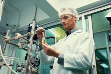 Bir bilim adamı ya da eczacı CBD kenevir yağını laboratuarda tıbbi amaçlar için çıkartıyor. Esrar çıkarma makinesinden üretilen alternatif esrar temelli ilaçlar.