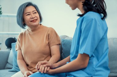 A contented senior woman visited by her personal caregiver and hold each others hands.