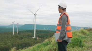 Kırsal kesimdeki bir tepenin tepesinde ya da dağda rüzgar çiftliğinde çalışan bir mühendis. Yenilenebilir ve sürdürülebilir enerjinin gelecekteki üretimi için yenilikçi bir ideal. Rüzgar türbininden enerji üretimi.