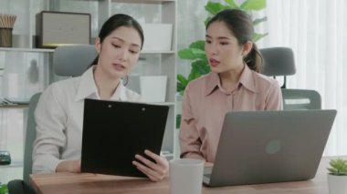 Ofis çalışma alanında birlikte çalışan iki genç hevesli iş kadını. Genç meslektaşlar tartışırken ve dizüstü bilgisayar kullanırken. Modern ofis çalışanları masada birlikte oturuyorlar..